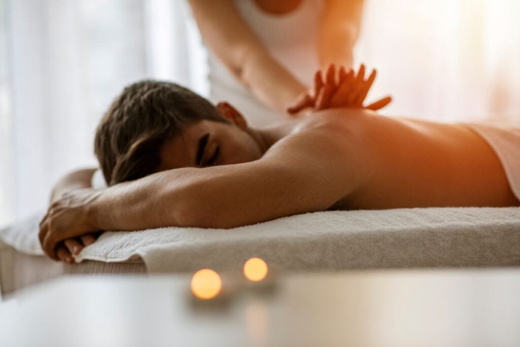 Homem deitado recebendo massagem nas costas em ambiente de spa relaxante