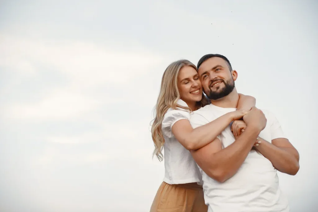 Casal jovem abraçado, sorrindo e com expressão de felicidade, com a palavra-chave "libido".