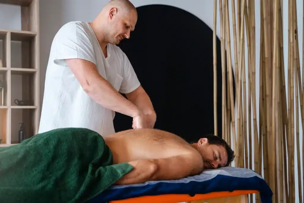 Terapeuta realizando massagem nas costas de um homem deitado