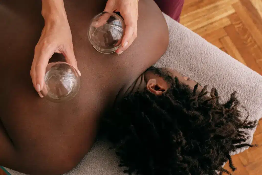 Profissional aplicando ventosaterapia nas costas de um homem para promover relaxamento e alívio da tensão muscular.
