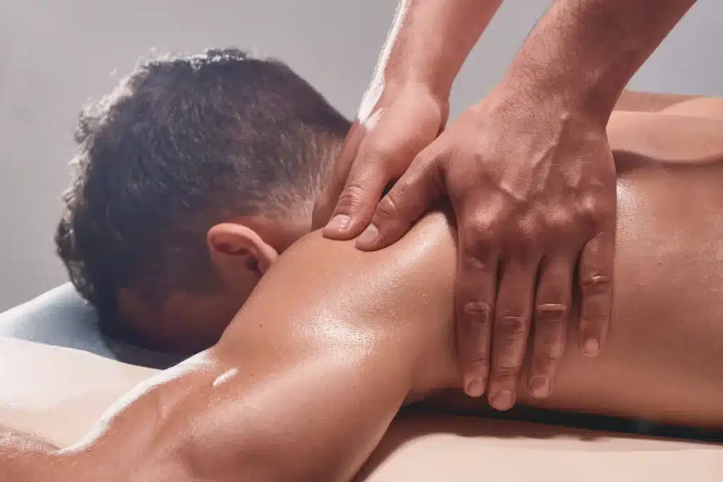 Homem recebendo massagem nas costas com técnica de pressão muscular, promovendo bem-estar e liberação de hormônios do prazer