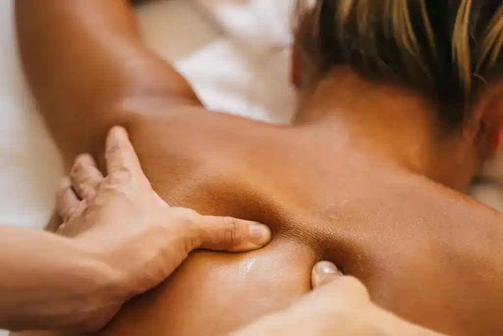Pessoa recebendo massagem profunda nas costas com pressão dos polegares, promovendo relaxamento muscular