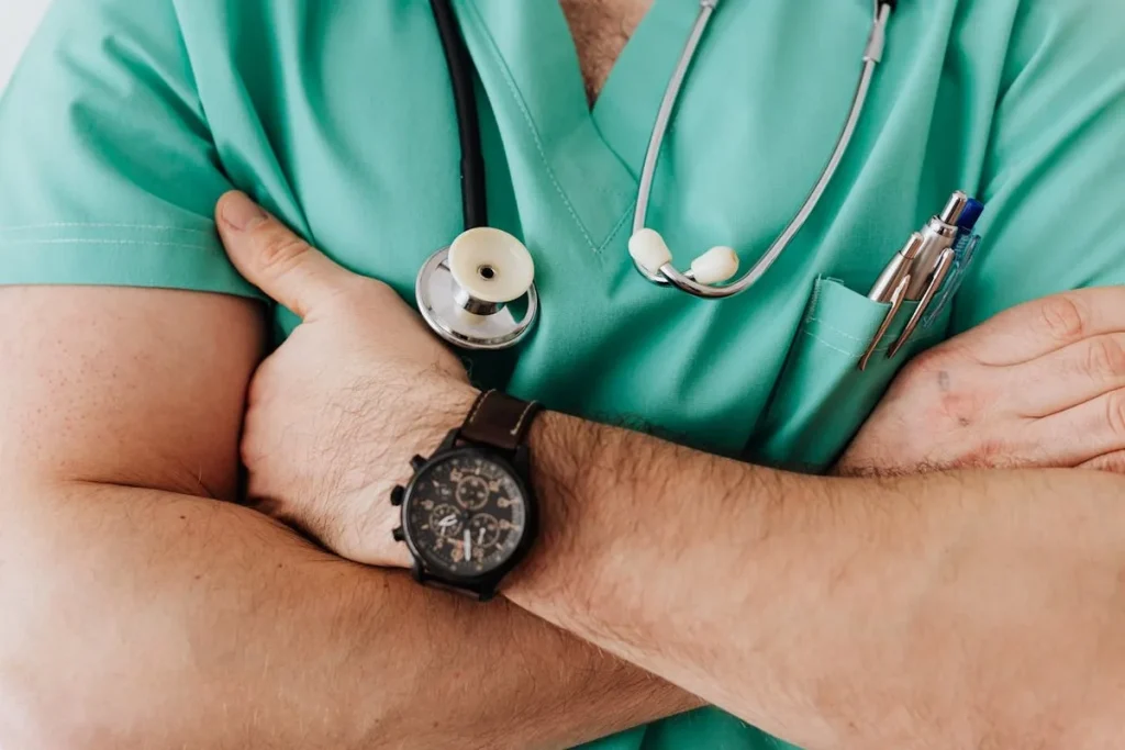 Médico urologista com jaleco verde e estetoscópio no pescoço.