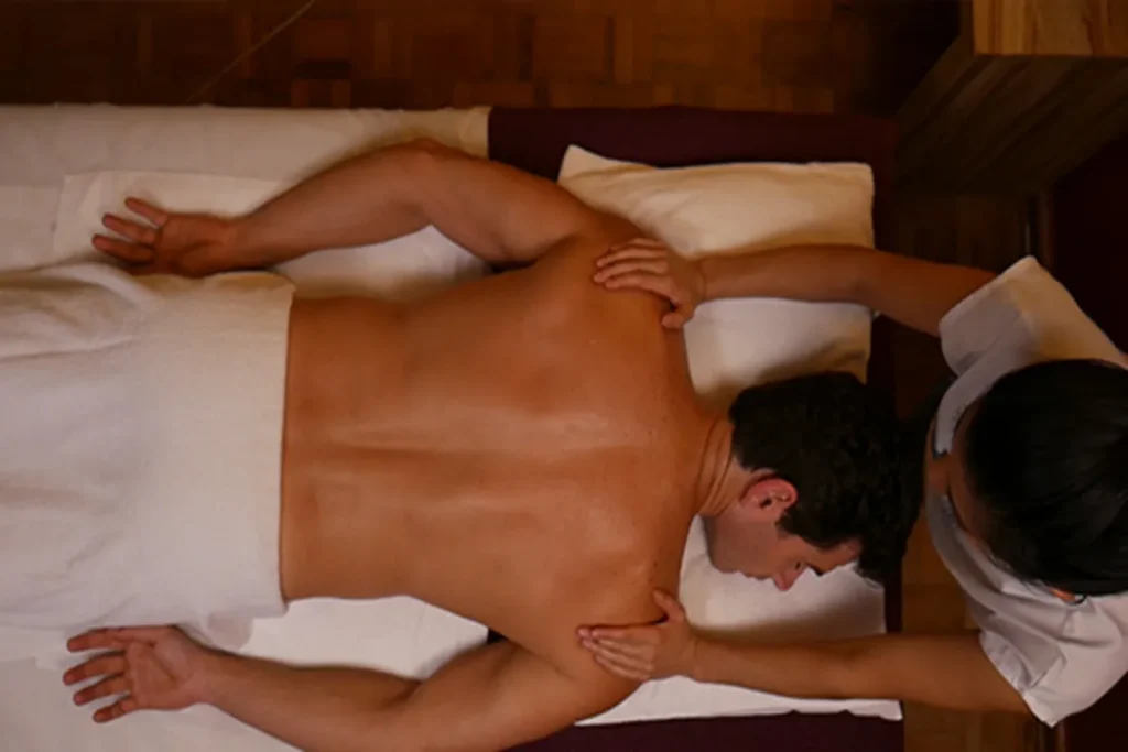 Homem recebendo massagem relaxante de bruços, representando virilidade, energia vital e equilíbrio físico.