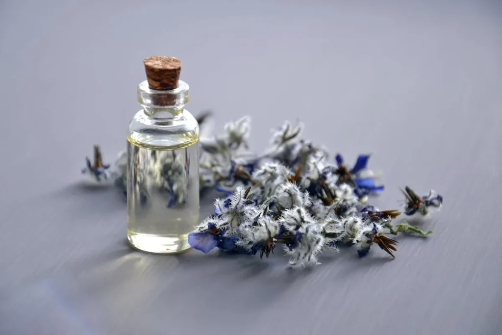 Frasco de óleo essencial e flores secas usados na aromaterapia para relaxamento e equilíbrio emocional.