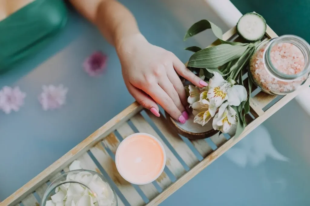 Banho aromático com flores, sais de banho e vela aromática para relaxamento e bem-estar.