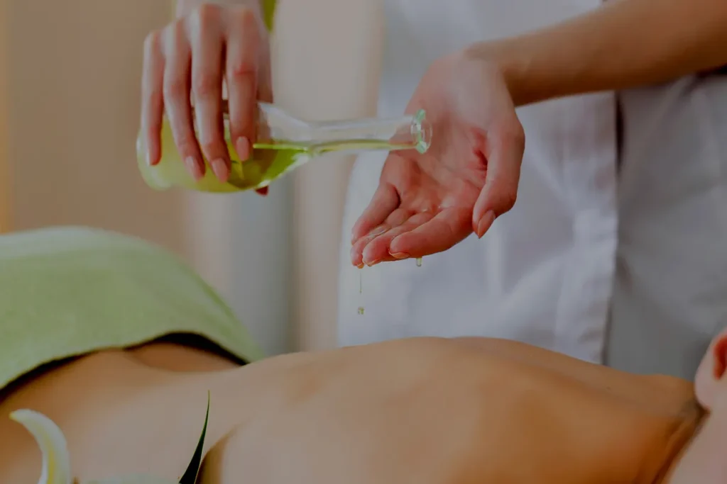 Massagista derrama óleo essencial em sua mão, representando o uso de aromaterapia para acalmar o sistema nervoso.