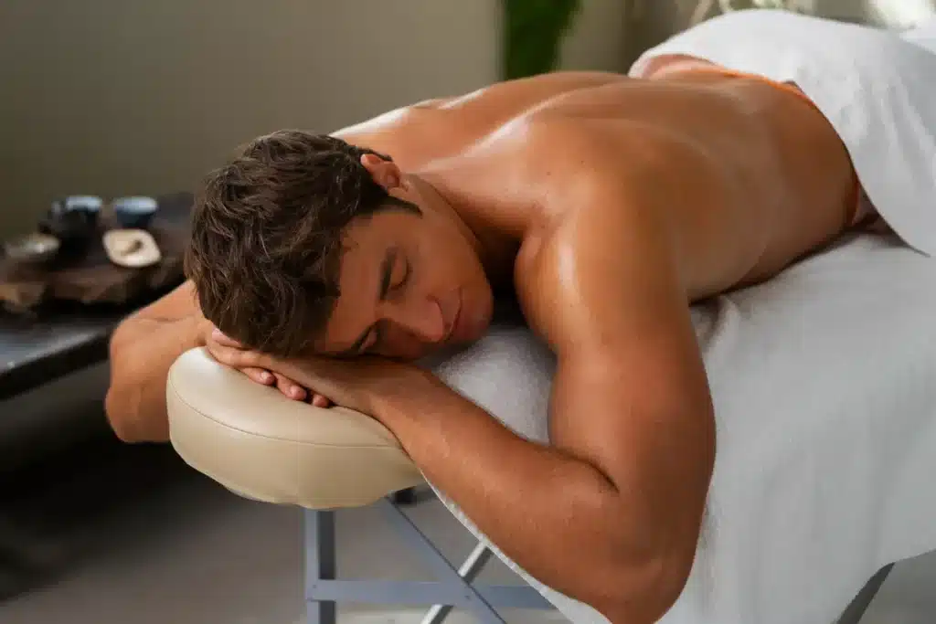 Homem deitado de bruços em uma maca de massagem, com os olhos fechados, indicando um estado de relaxamento e foco na percepção sensorial.