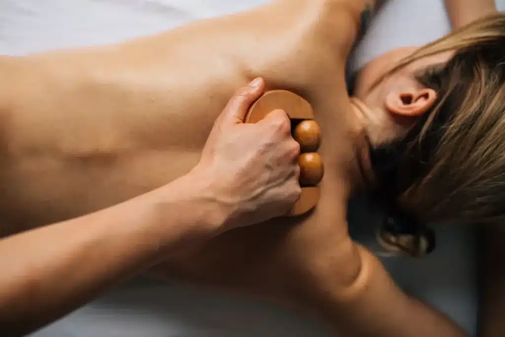 Uma pessoa recebendo uma massagem relaxante nas costas com uma ferramenta de madeira, focando no bem-estar e na ativação do sistema nervoso parassimpático.