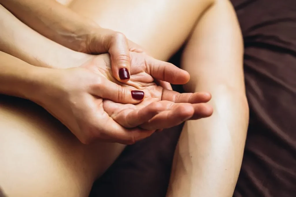 As mãos de um terapeuta aplicando uma massagem de kundalini nas costas de uma pessoa.