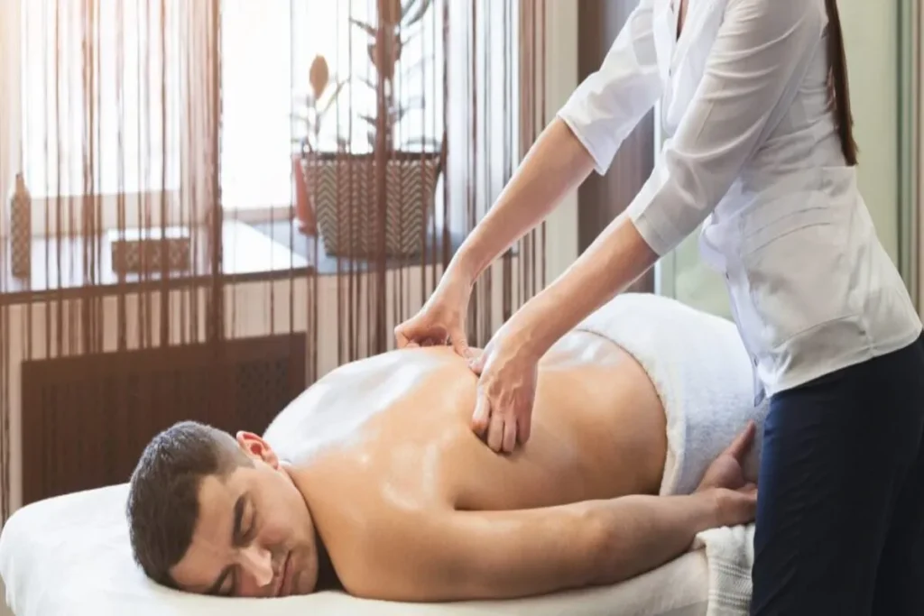 Massagista em um curso massoterapeuta aplica massagem nas costas de cliente.