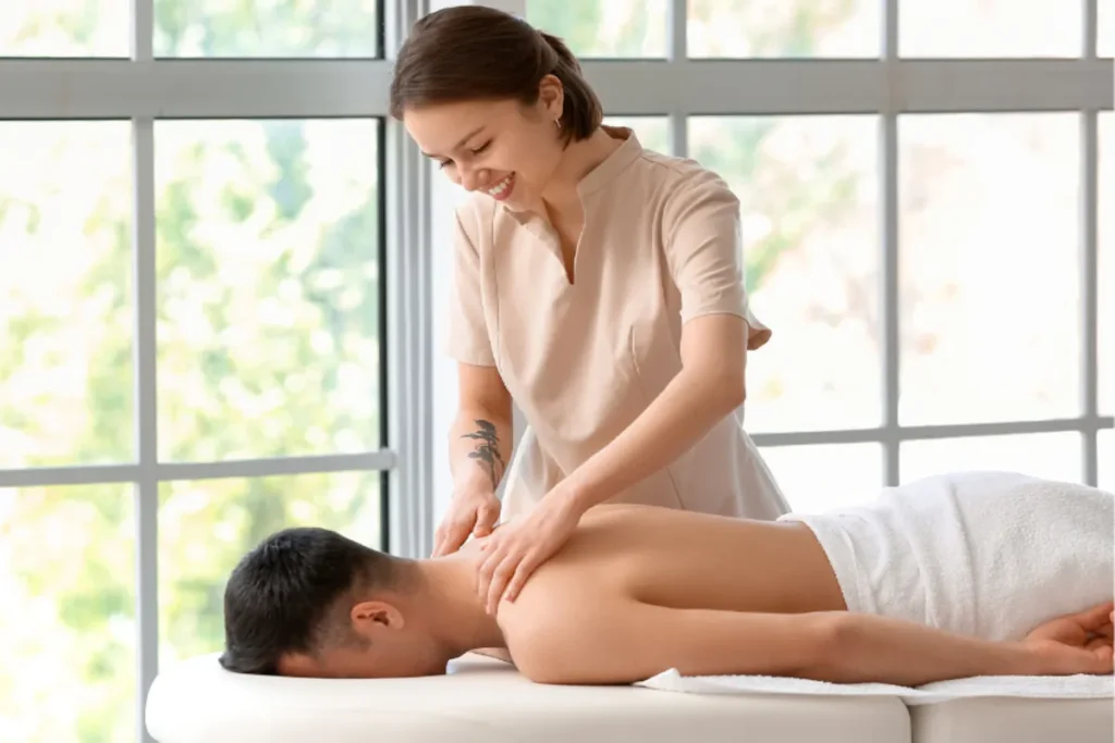 Massagista sorridente em um curso massoterapeuta aplica massagem nos ombros de um cliente.