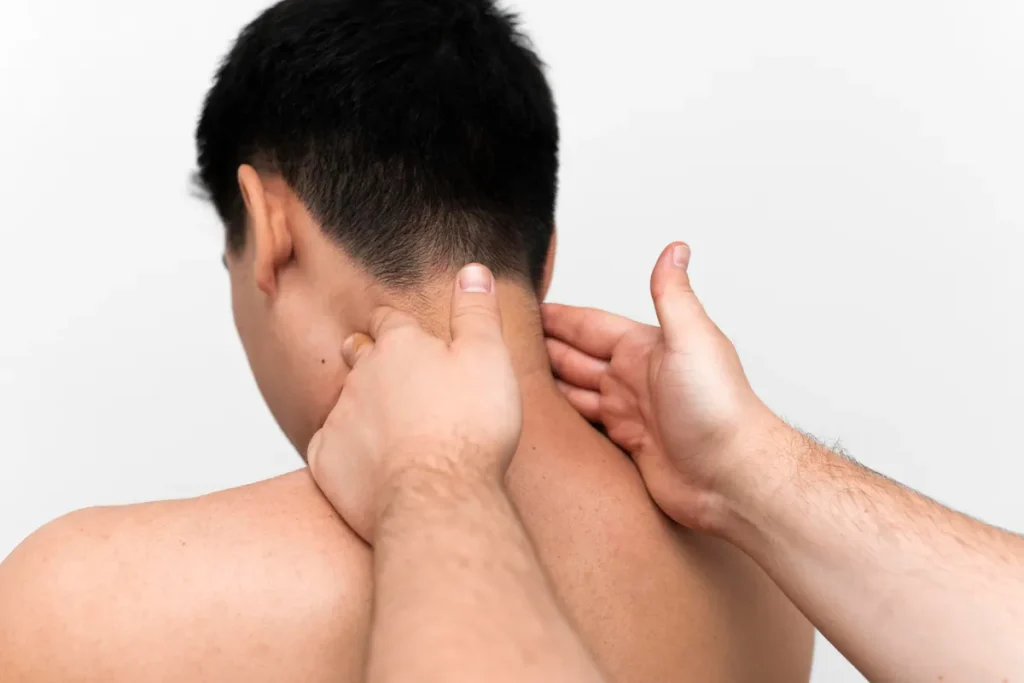 Close-up de terapeuta aplicando massagem terapêutica profunda nos músculos do pescoço e ombros de um paciente.