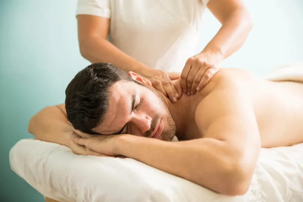 Homem jovem recebendo massagem relaxante nas costas em ambiente simples para tratamento do estresse emocional.