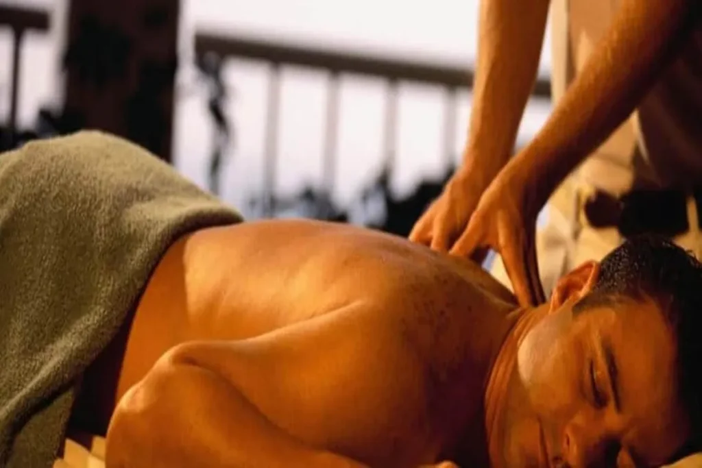 Homem recebendo massagem nas costas com aplicação de gel lubrificante para relaxamento muscular.