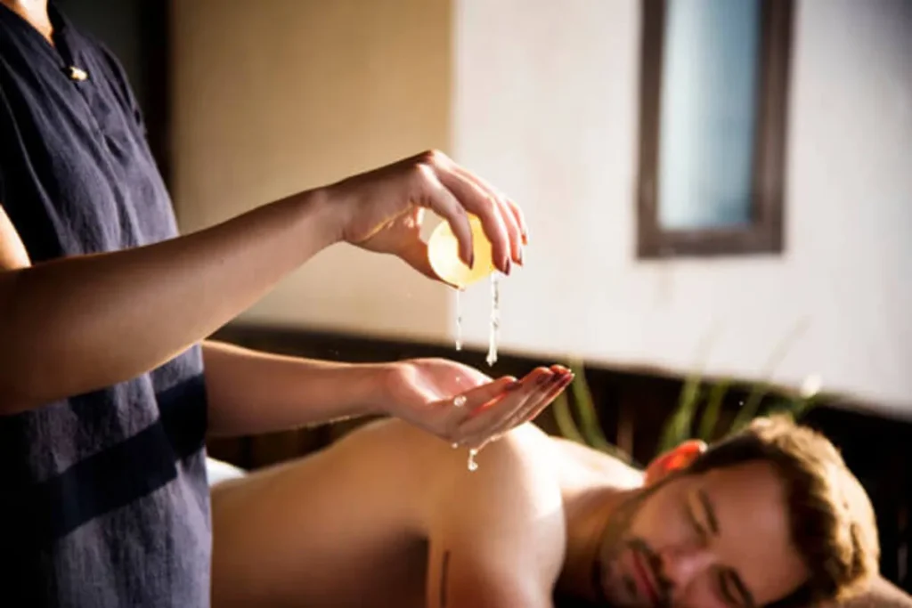 Óleo sendo derramado nas mãos do terapeuta para sessão de massagem Kundalini em ambiente relaxante