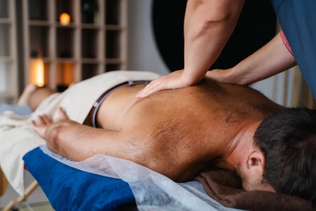 Terapeuta aplicando massagem miofascial profunda nas costas de um homem, focando na liberação de pontos de tensão muscular.