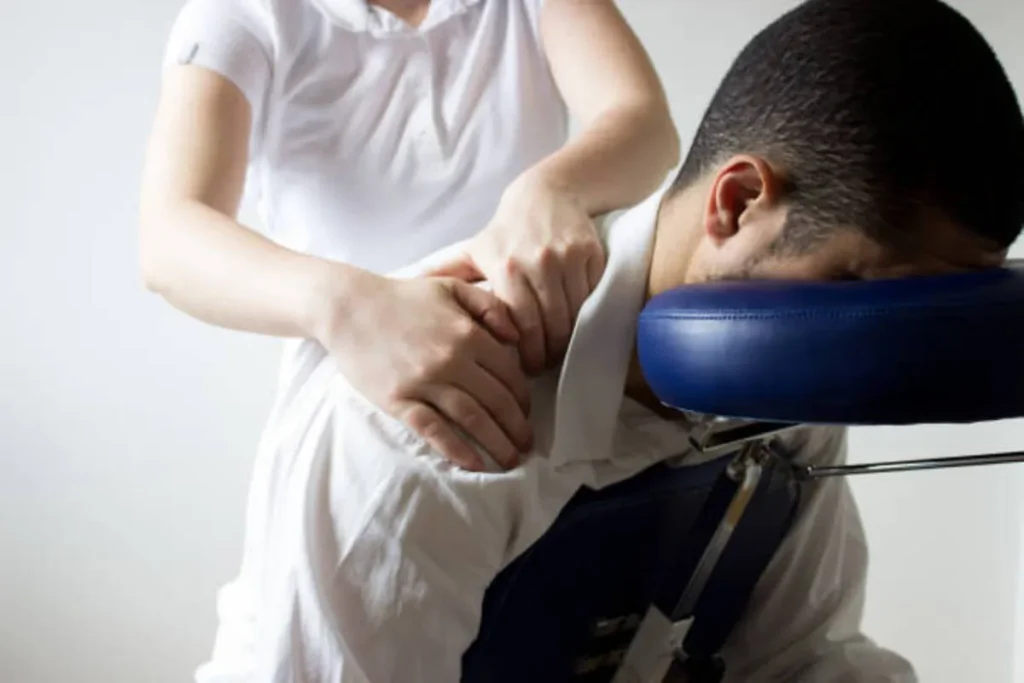 Homem recebendo quick massagem em cadeira ergonômica.