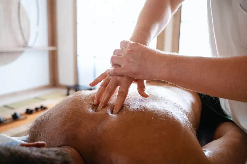 Homem recebendo massagem terapêutica profunda nas costas com óleo.