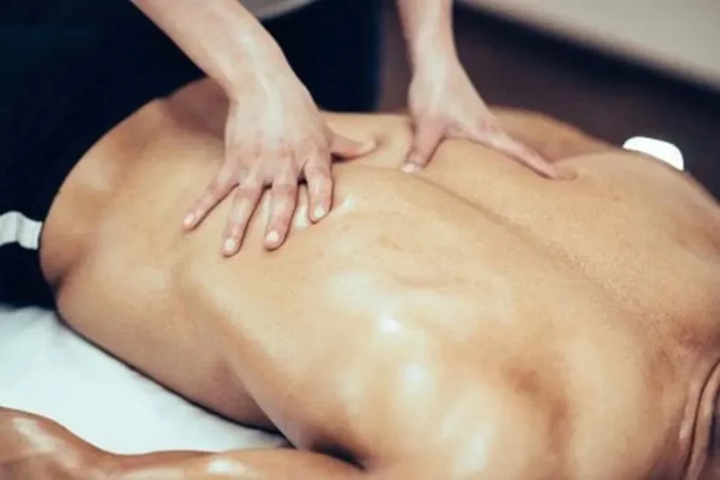Terapeuta realizando massagem nas costas de um homem para estimular o sistema linfático e melhorar a circulação.