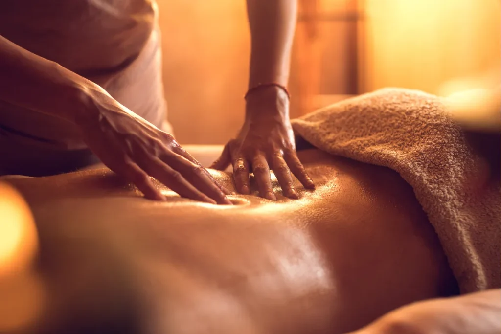 Profissional aplicando massagem relaxante nas costas de uma pessoa em um ambiente de spa com iluminação suave e atmosfera acolhedora.