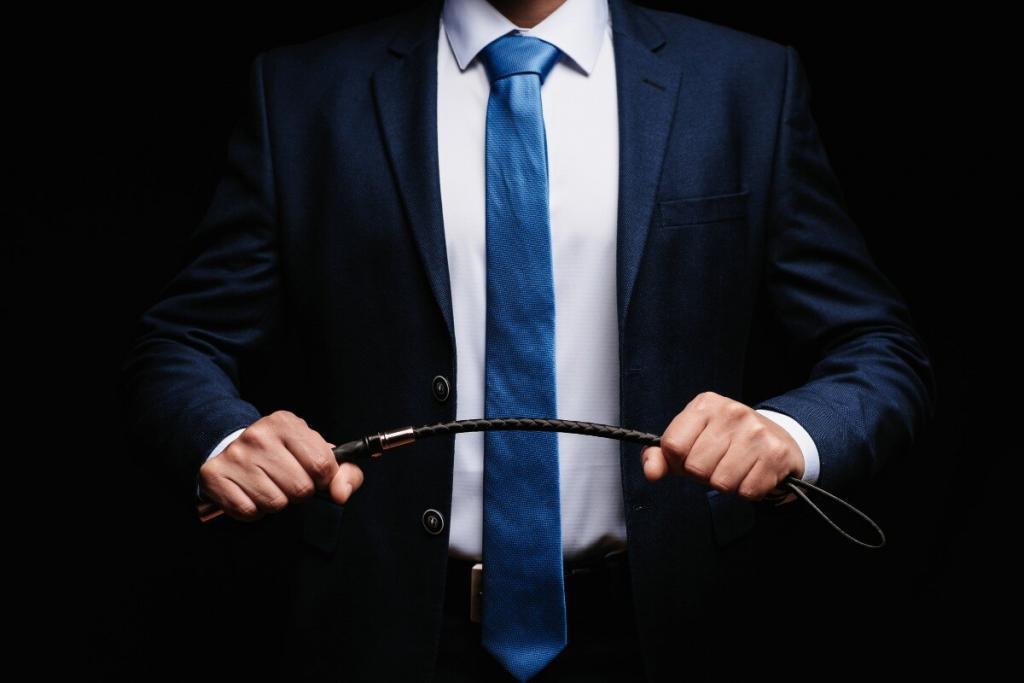 Homem de terno azul e gravata segurando um chicote de couro nas mãos, simbolizando poder e controle