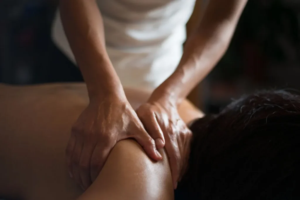 Profissional realizando massagem relaxante terapêutica nas costas de uma mulher em ambiente de spa.