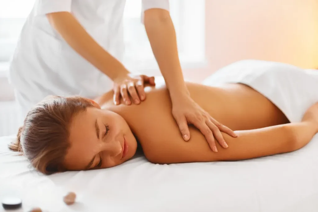 Mulher deitada recebendo massagem relaxante nas costas em uma maca de spa.