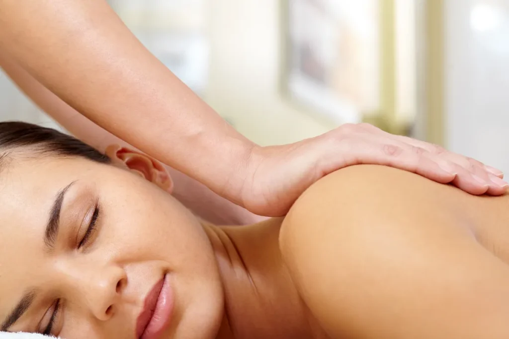 Mulher relaxando durante massagem terapêutica na região superior das costas em ambiente claro e confortável