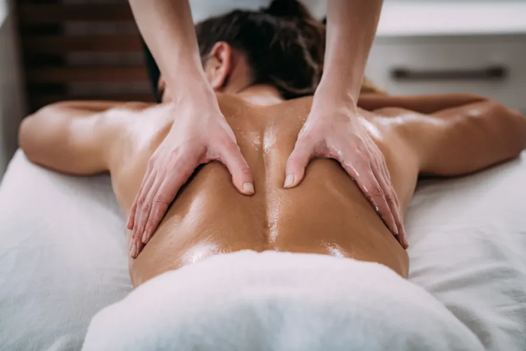 Aplicação de óleo nas costas com movimentos contínuos durante massagem, destacando o deslizamento das mãos