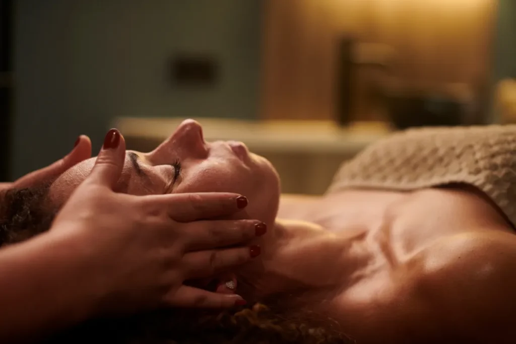 Pessoa recebendo massagem no rosto em ambiente com iluminação suave e atmosfera acolhedora