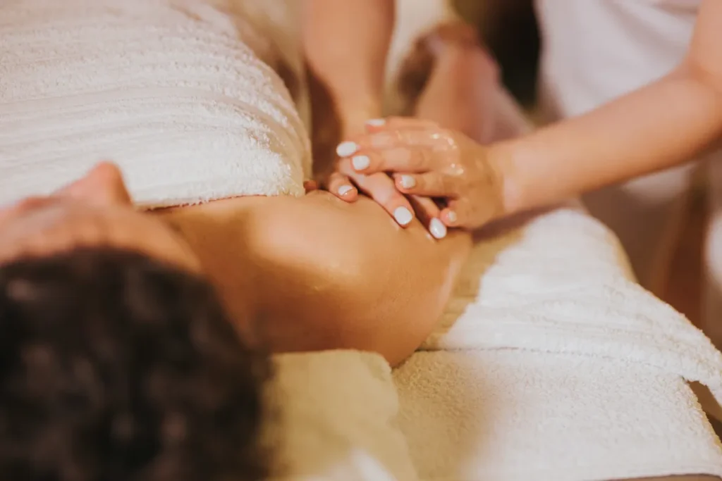 Profissional aplicando movimentos de massagem terapêutica nas costas com óleo corporal em ambiente tranquilo