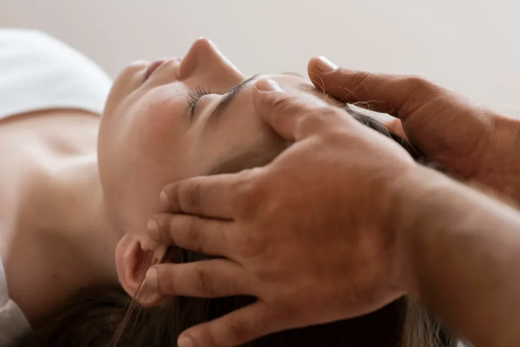 Terapeuta aplicando shiatsu na cabeça de mulher deitada durante sessão voltada ao relaxamento e equilíbrio energético.