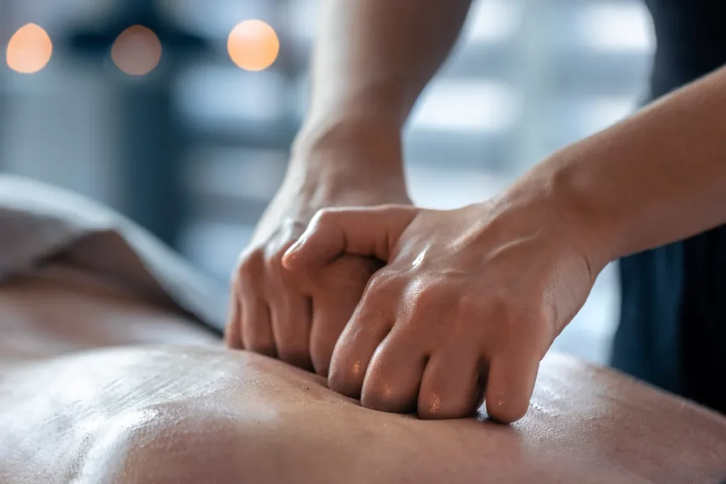 Aplicação de pressão com as mãos nas costas durante atendimento de shiatsu para aliviar dores musculares.