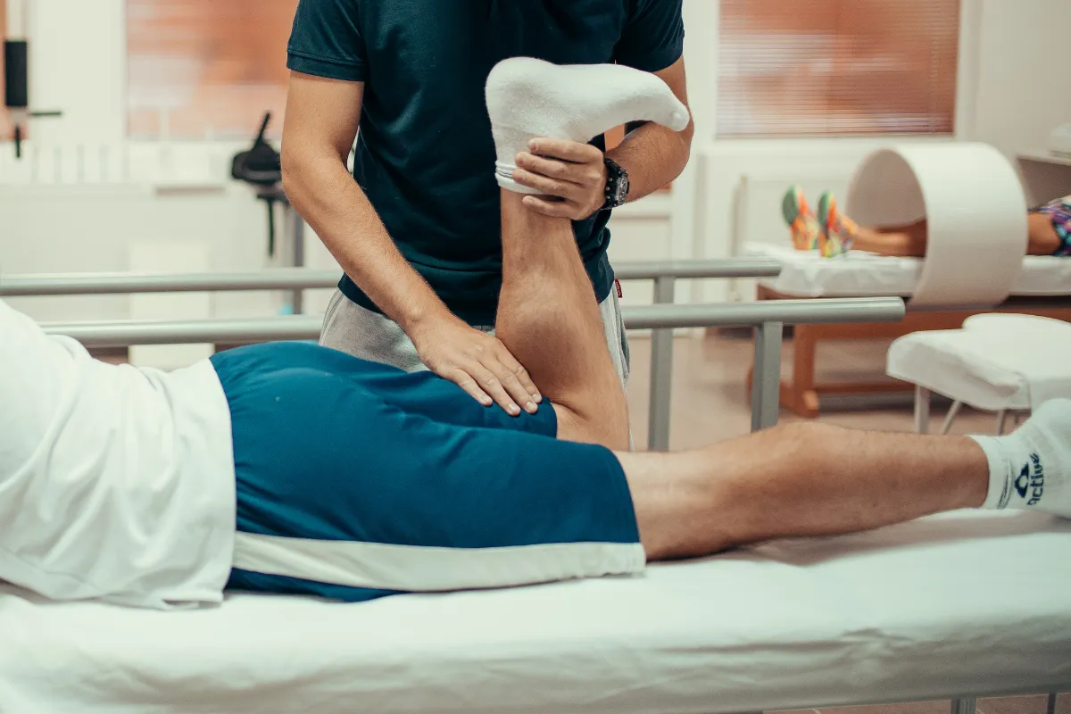 Fisioterapeuta avalia a mobilidade da perna de um paciente