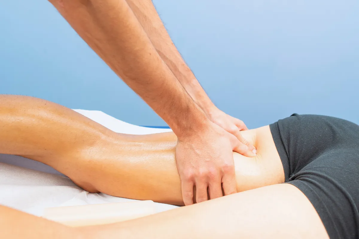 Profissional realizando terapia manual na região posterior da coxa durante etapa de recuperação