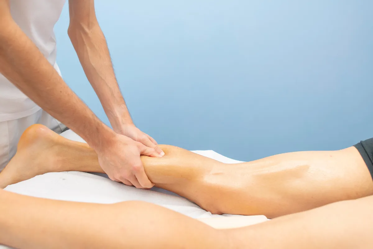 Fisioterapeuta segurando o joelho e a perna de paciente durante atendimento